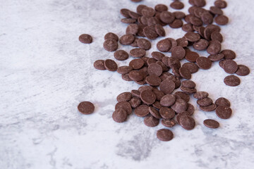 Chocolate drops (callets) on a light background. Side view. Copy space.