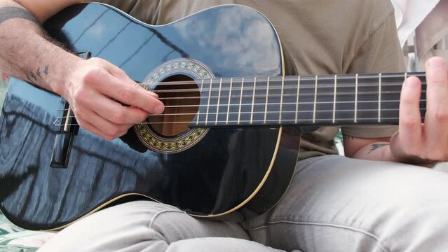 Caucasian young man playing acoustic guitar on home terrace
