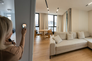 Woman using smartphone to control home connectivity interface.