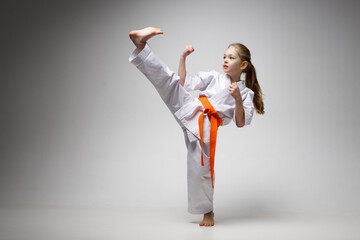 Strong kick in karate training, sporty little girl.