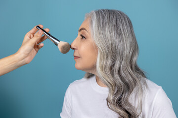 Obraz premium Beautiful smiling senior woman doing makeup