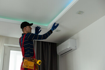 An electrician is installing LED spotlights on the ceiling.