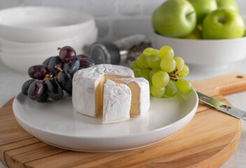 Brie or soft cheese, with dark and green grapes on a plate