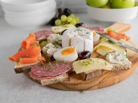 Platter with cold cut sandwiches on a wooden cutting board on kitchen table