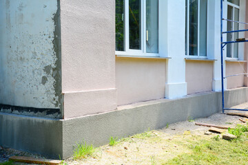 Painting house wall outdoors. Old house facade renovation with stucco and painting walls.