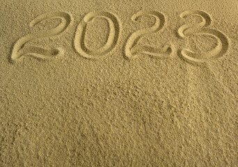 Fototapeta na wymiar Signpost 2023 written in sand. There is space for text.