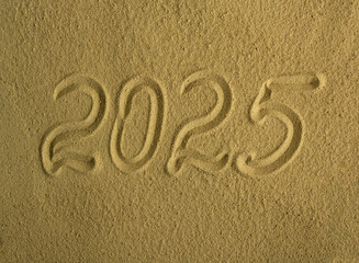 The inscription 2025 on the sea sand. Beautiful holiday background.