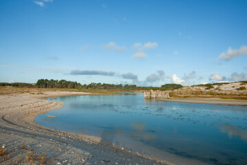 Stream running through sand dunes to beach