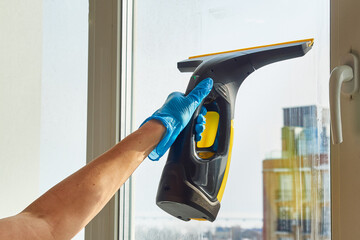 Woman's hand cleaning the window with a professional vacuum cleaner
