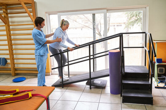 Physiotherapist assisting elderly woman in movement therapy