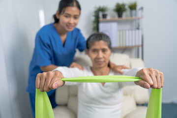 Concept of World Confederation for Physical Therapy. young physiotherapist caregiver helping mature elderly woman training with elastics in rehabilitation center, muscle weakness