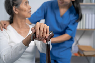 Attentive practitioner nurse assisting physical therapy elderly woman on a walking wood standard...