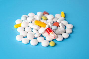 Pile, heap of different pills on blue background, concept medical picture