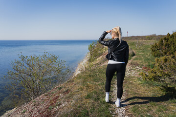 Fototapeta premium Traveler girl walking in nature near the sea cliff in Paldiski on a spring day.