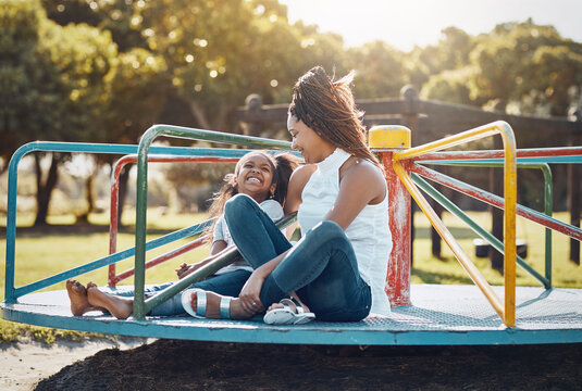 Woman, young girl together on roundabout at park and playing with smile and fun outdoor. Love, care and bonding with family happiness, mother and daughter enjoying time at playground with freedom