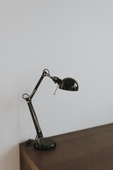 Lamp on wooden table near white wall