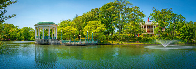 Fototapeta na wymiar Bandstand Pavilion and water fountain on the Roosevelt Lake and forest at Roger Williams Park, Providence, Rhode Island