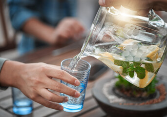 Hands, closeup and water into a glass, outdoor and social gathering with friends, drink and cool...