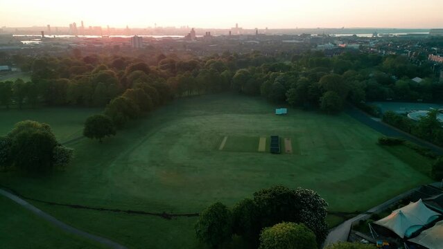 Birkenhead Park, upon which Central Park NY is based - Aerial drone at dawn, cricket oval flyover and lake approach, Liverpool skyline backdrop - May 23