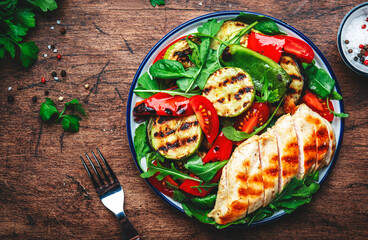 Grilled vegetables and chicken fillet salad with spinach. Paprika, zucchini, eggplant, tomatoes on rustic wooden table background, top view - obrazy, fototapety, plakaty