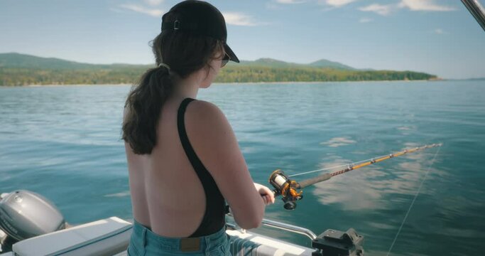 Young woman fishing off a boat on a sunny day
