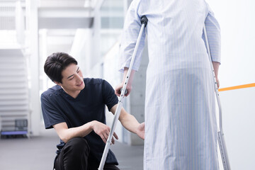 リハビリや介護のイメージ　松葉杖と患者を支える理学療法士 - obrazy, fototapety, plakaty