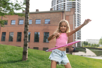 Little girl playing with hula hoop in city park. - obrazy, fototapety, plakaty