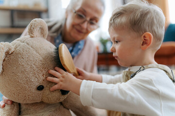 Little boy and grandmother take care of the stuffed toy.
