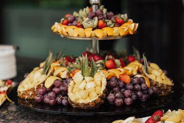 Plate with different kind of fruits. Luxury gorgeous wedding buffet with oranges, grape, pineapple, strawberries and kiwi.	