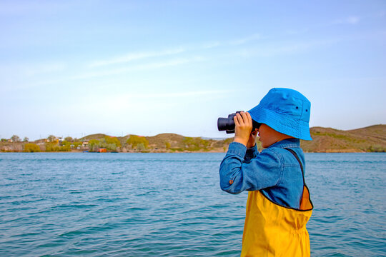 a little fisherman boy looks into a binocole