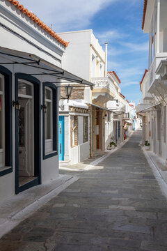 Greece, Cyclades. Andros island, Chora town. Empty alley white wall blue sky background. Vertical