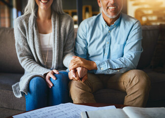 Holding hands, happy senior couple and life insurance support with paperwork in a living room....
