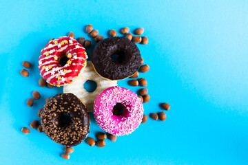 Donut with hazelnuts on blue background, close up