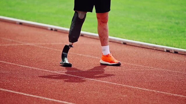 Cinematic close-up of a disabled man with a prosthetic leg on a treadmill. The concept of an active life position of disabled people, their determination and motivation.
