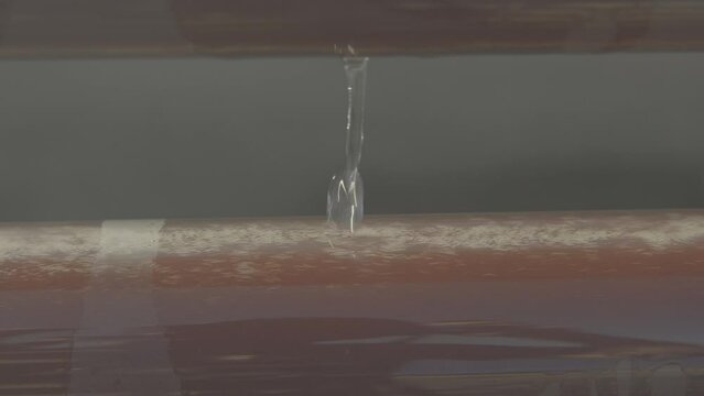 A close-up of red algae water, runs through transparent pipes under the sun, with cooling water that drips on top of the pipe. a beautiful slow motion, 4K. (F-log) video clip.