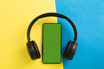 Big wireless headphones and phone. Chromakey space on the phone screen