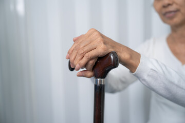 physical therapy elderly woman on a walking wood standard cane in disability nursing rehabilitation center.