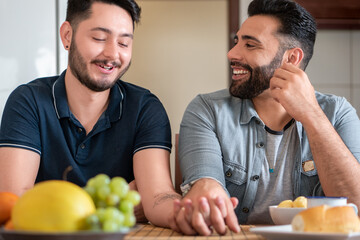 happy gay man smiling and holding hand with partner at table