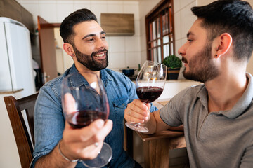 happy gay couple enjoying wine and talking at home