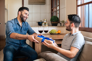 romantic gay man giving gift box to partner at home