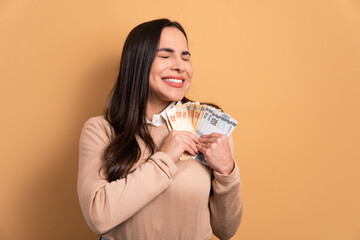 fun brunette young woman celebrating successful business money in all beige colors. business, loan,...