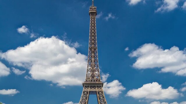 Eiffel Tower on Champs de Mars in Paris timelapse hyperlapse, France. Blue cloudy sky at summer day with green lawn and people walking around. Moving forward