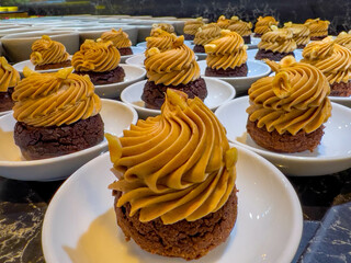 pumpkin, caramel or orange cream on a chocolate biscuit. cupcakes on a small plate. at catering event on some festive event, restaurant, party or wedding reception