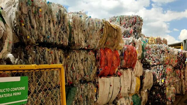 Panning clip showing organised bales of plastic waste at recycling centre