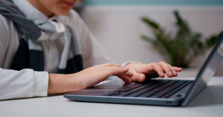 Close-up of hands typing on a computer keyboard student searching information at living room at home.