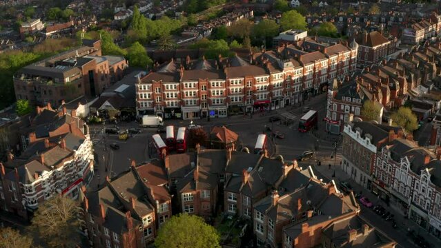 Low circling aerial shot around roundabout panning up to Muswell hill broadway and st James Church