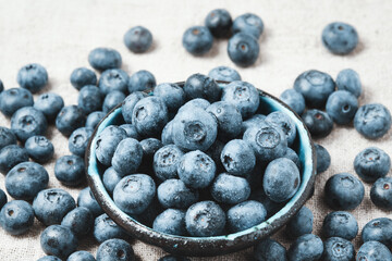Blueberries with water drops in a ceramic bowl and scattered around.