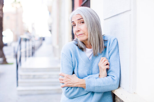 senior retired pretty white hair woman shrugging, feeling confused and uncertain, doubting with arms crossed and puzzled look