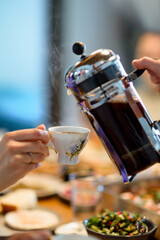 Girl pours coffee into a porcelain cup for breakfast