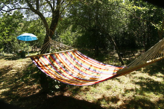 Un hamac &agrave; rayures color&eacute;es deux places dans un jardin